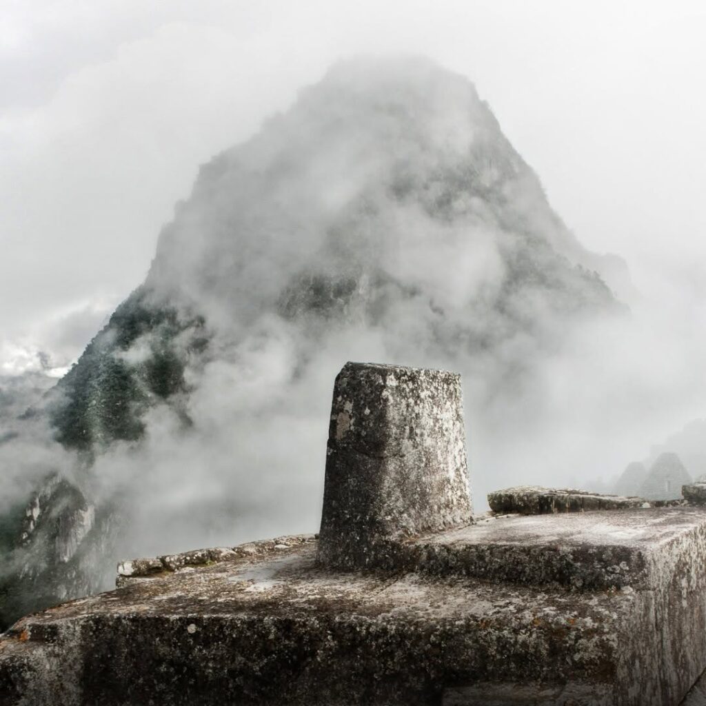 Intihuatana Stone in Machu Picchu city with clouds and rain